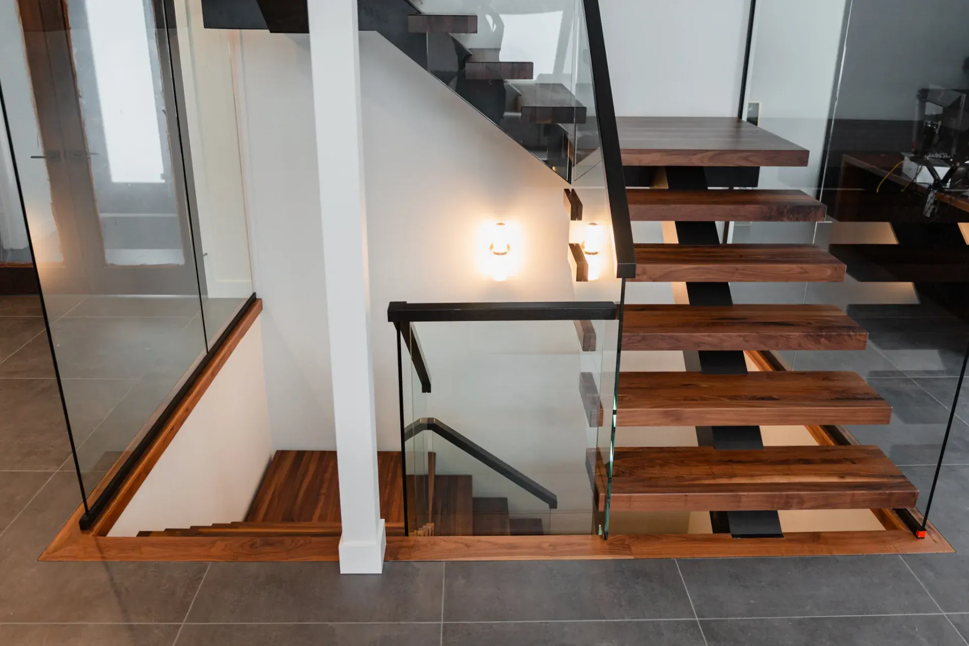 Escalier flottant en noyer massif, limon central acier noir et garde-corps verre trempé, double volée résidence contemporaine
