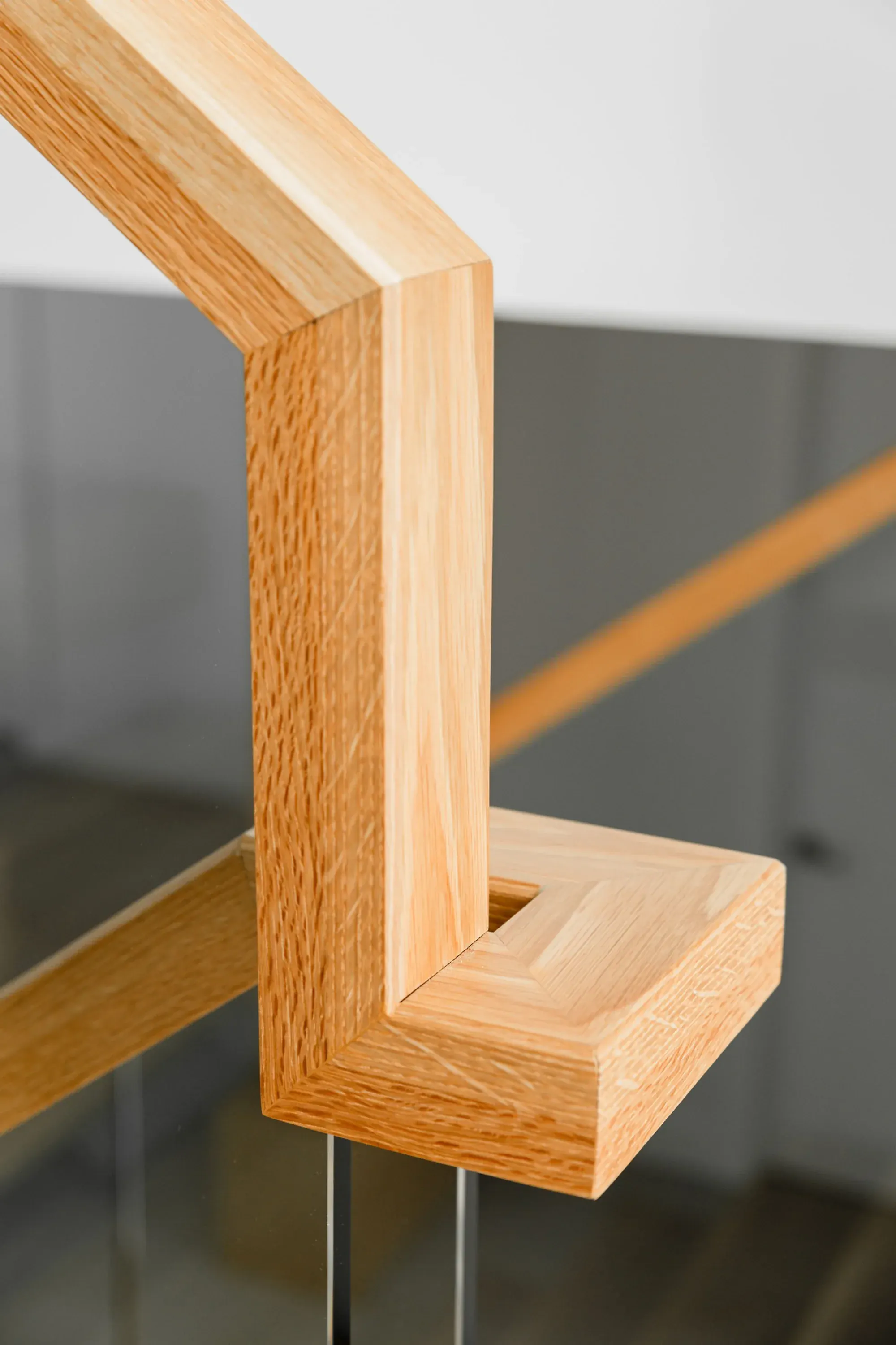 Détail rampe en chêne blanc massif usinée en L avec garde-corps verre, travail de précision sur mesure