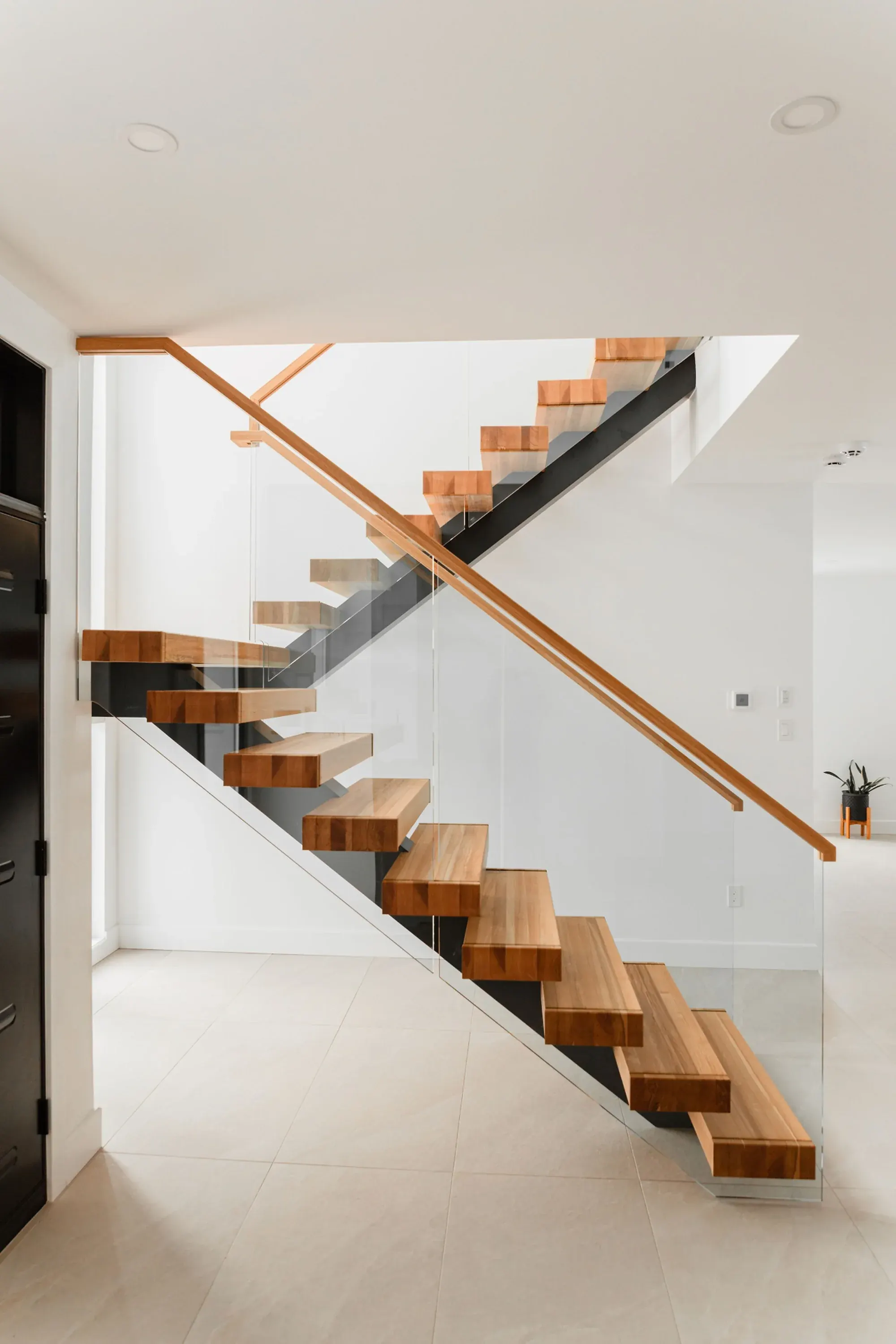 Escalier en chêne blanc double volée, limon central acier noir et garde-corps verre, rampe chêne blanc continue