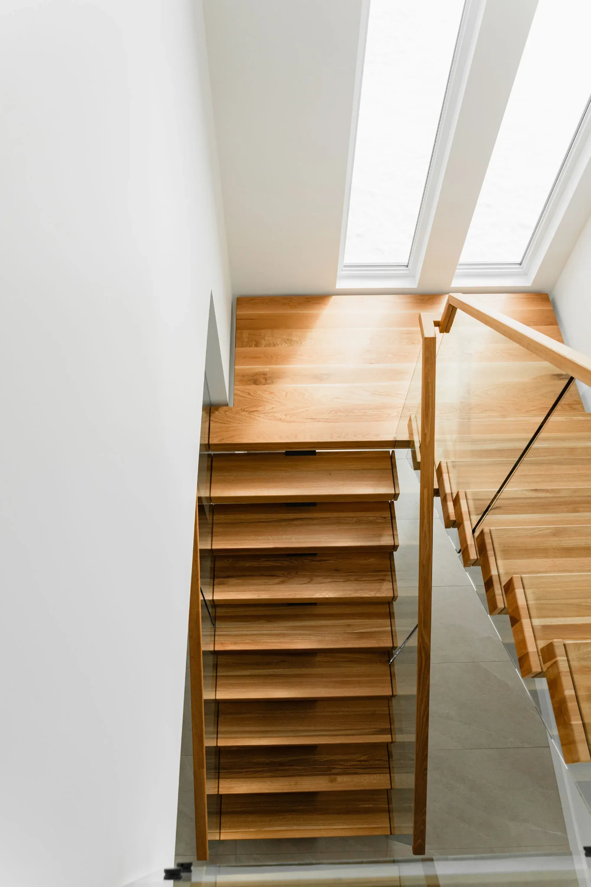 Escalier flottant en chêne blanc, limon central acier noir et garde-corps verre, résidence moderne épurée