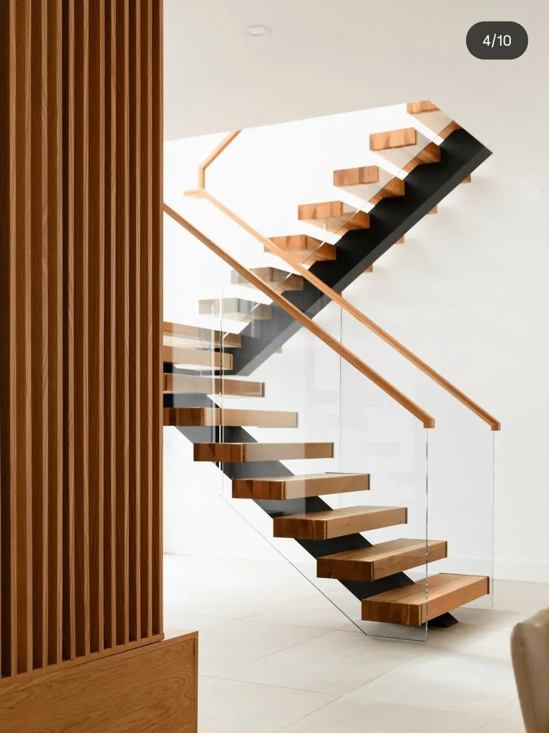 Escalier en noyer massif vu depuis salle à manger, limon central acier noir et rampe câble, résidence chalet de prestige