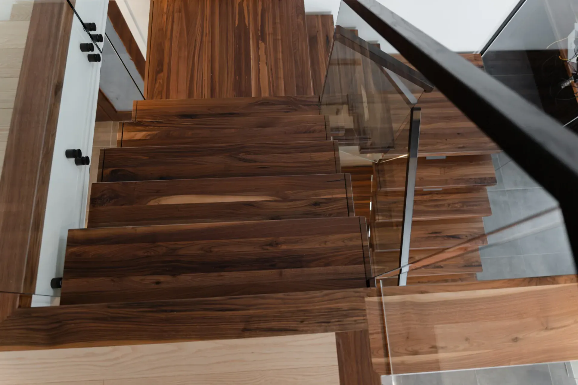 Escalier flottant en noyer massif, limon central acier noir et garde-corps verre, salon ouvert avec éclairage LED